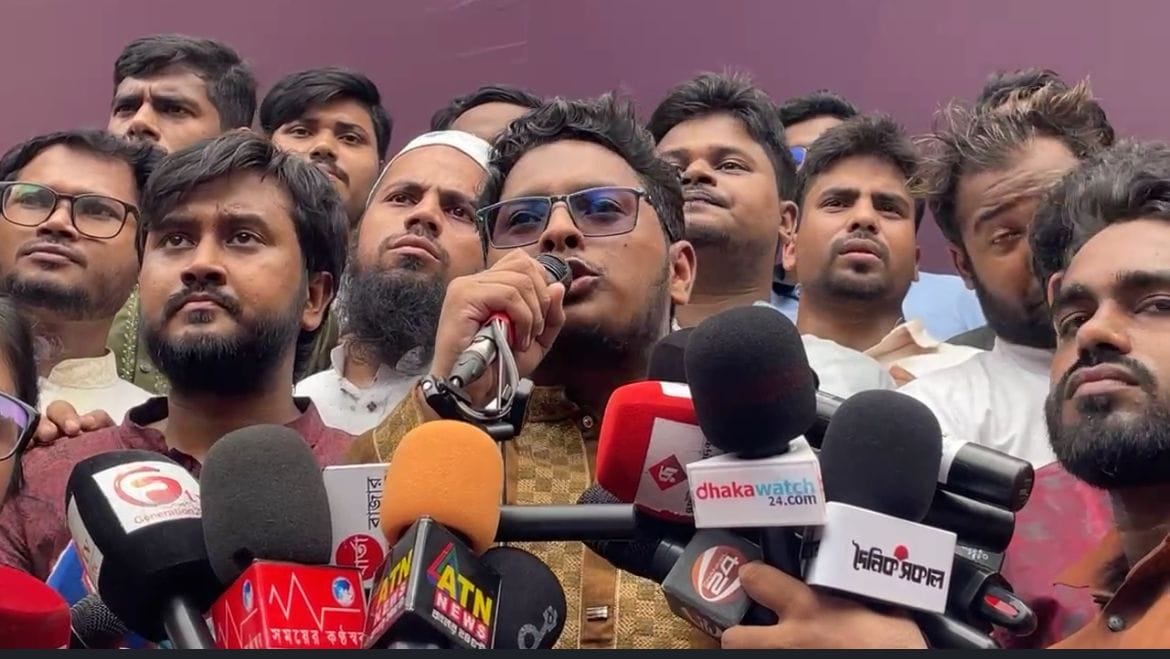 সংবাদ সম্মেলনে ভিড় করা মাইক্রোফোনের সামনে বক্তব্য দিচ্ছেন নাজমুল হাসান