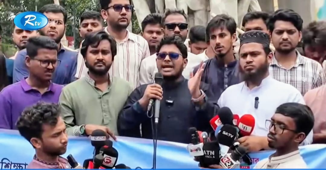 আরটিভির প্রতিবেদনে ব্যানারের সামনে মাইকে বক্তব্যরত নাজমুল হাসান, সামনে বিভিন্ন গণমাধ্যমের মাইক্রোফোন
